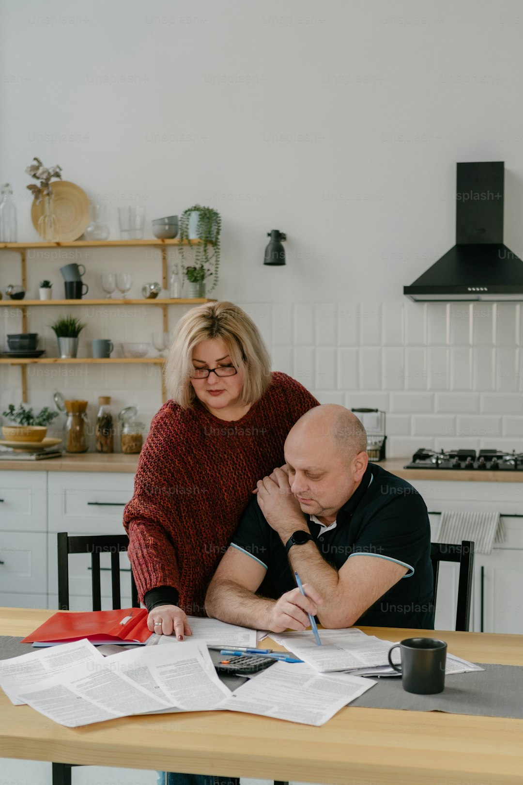 Person looking stressed at kitchen table with council tax bills and financial documents